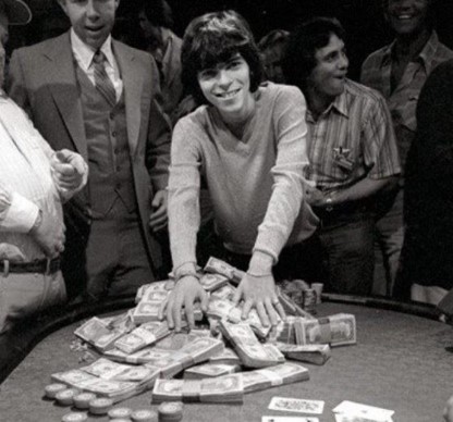 Poker legend Stu Ungar leaning over a pile of cash.