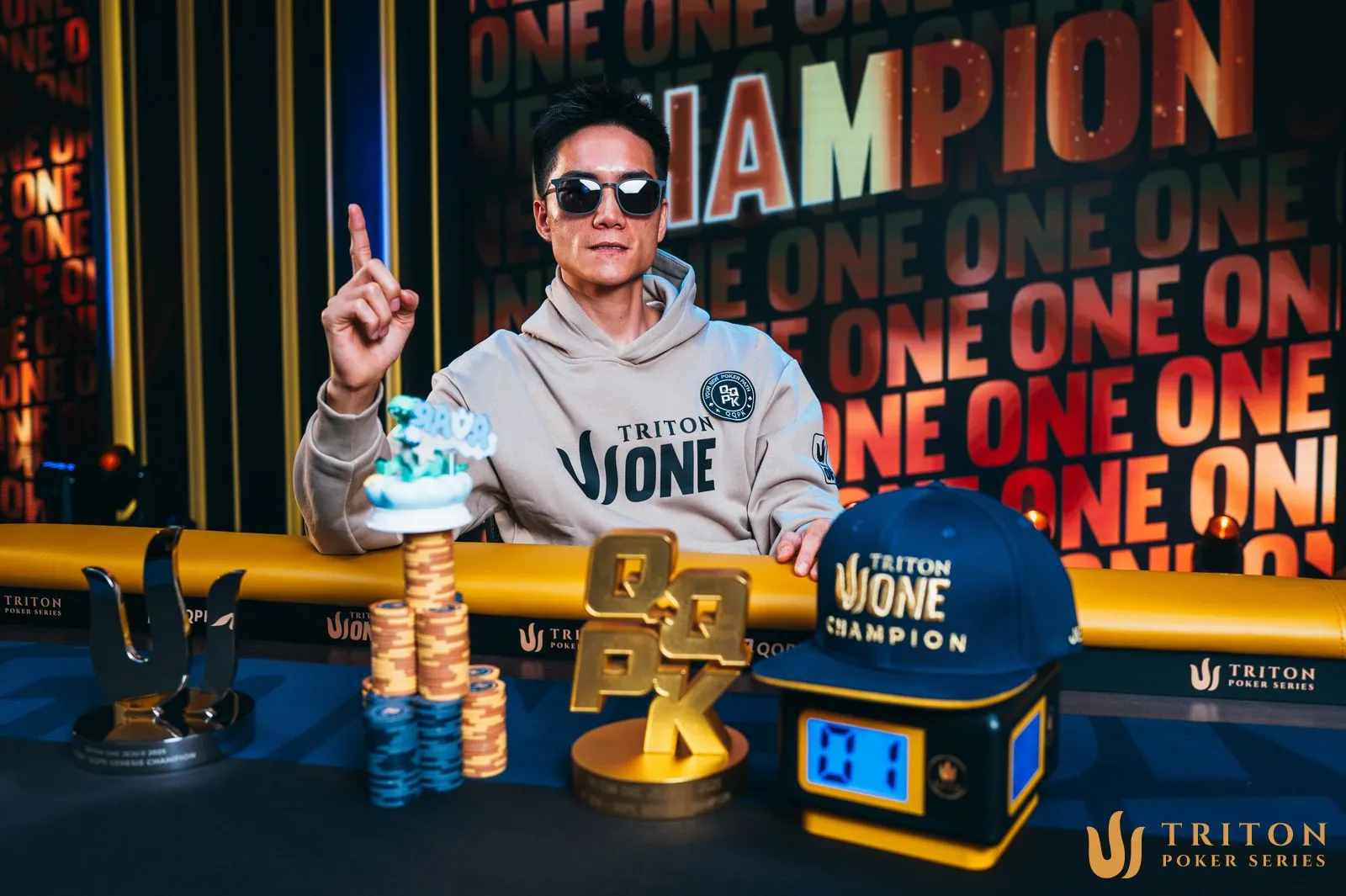 Chengxu is sitting at the table with a prize at Triton.